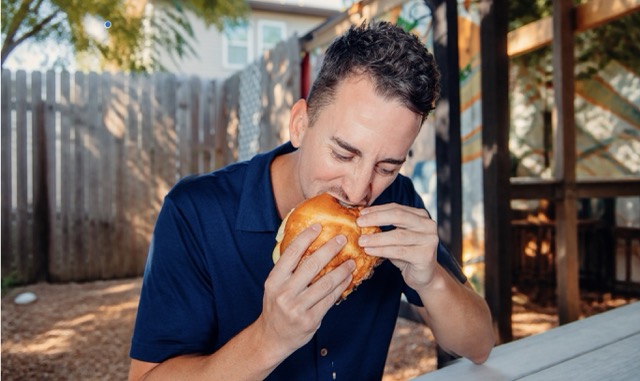 Person eating a torta on the patio at Austin Daily Press in East Austin